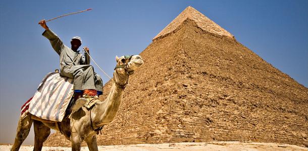 Mies ja kameli pyramidin edustalla