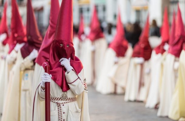 Punaiseen terävään huppuun ja valkoiseen kaapuun pukeutuneita pääsiäisjuhlijoita