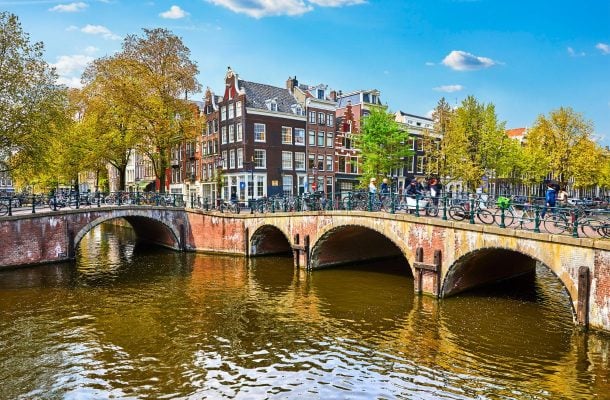 Kanaalin ylittävä silta, jonka edustalla värikkäitä taloja Amsterdamissa.