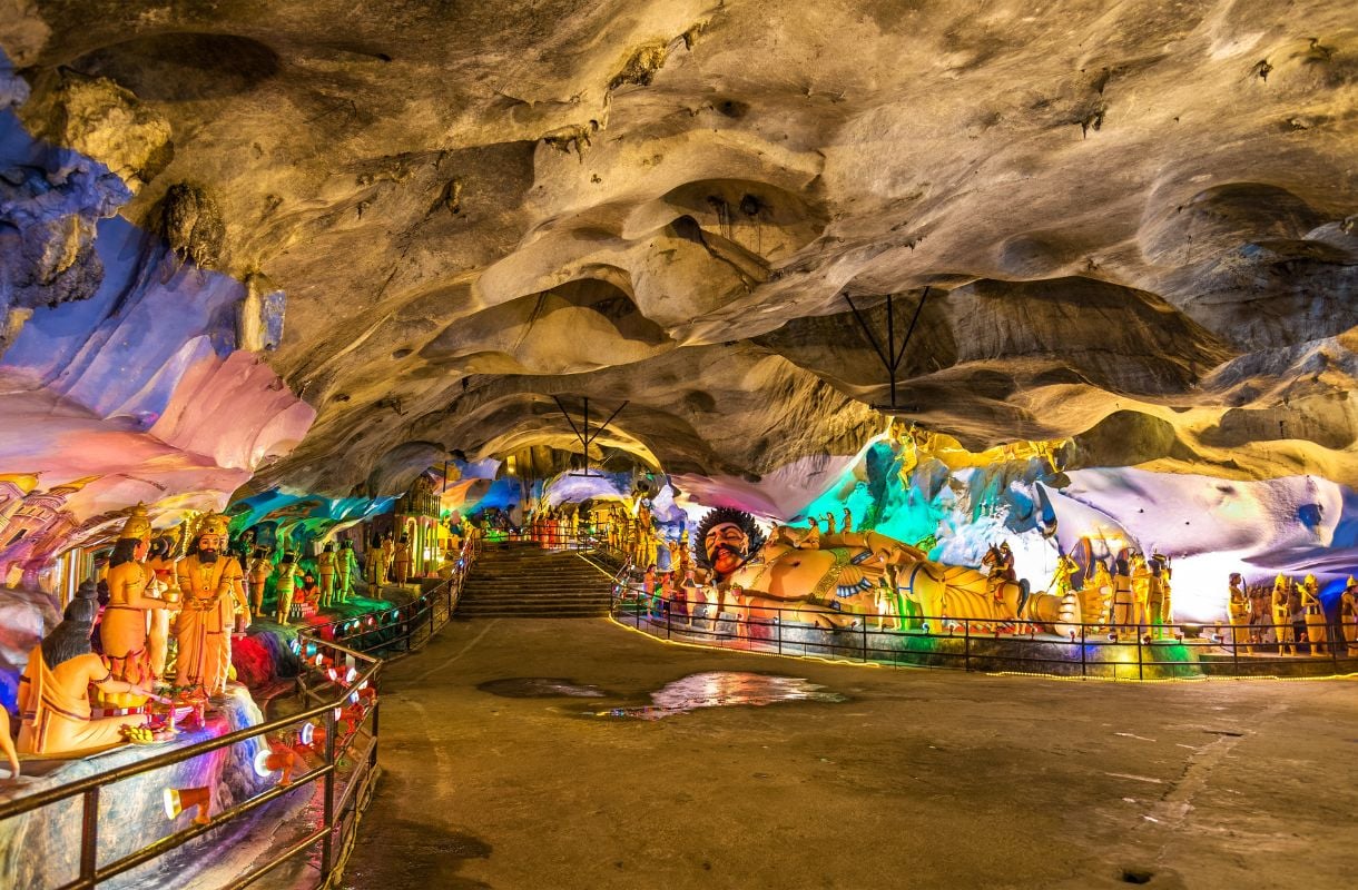 Matala luolasto, joka on täynnä värikkäitä hindulaisjumalten patsaita. Tyhjä käytävä etualalla.
