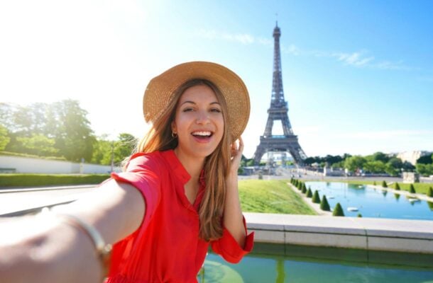 Iloinen nainen Eiffel-tornin edessä Pariisissa